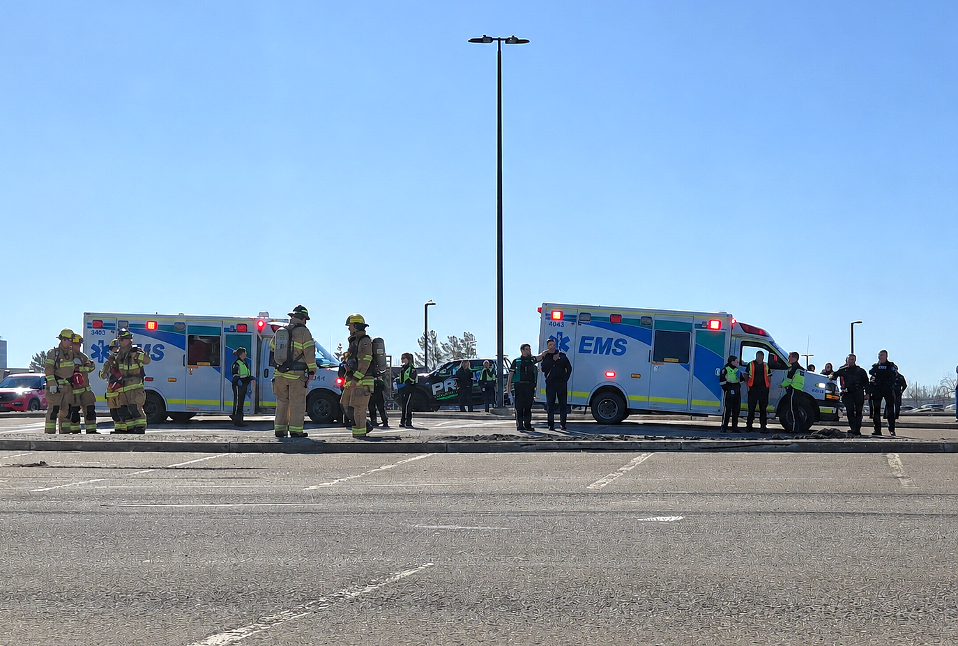 Two Ambulances parked in an open parking lot with firefighters standing ready.